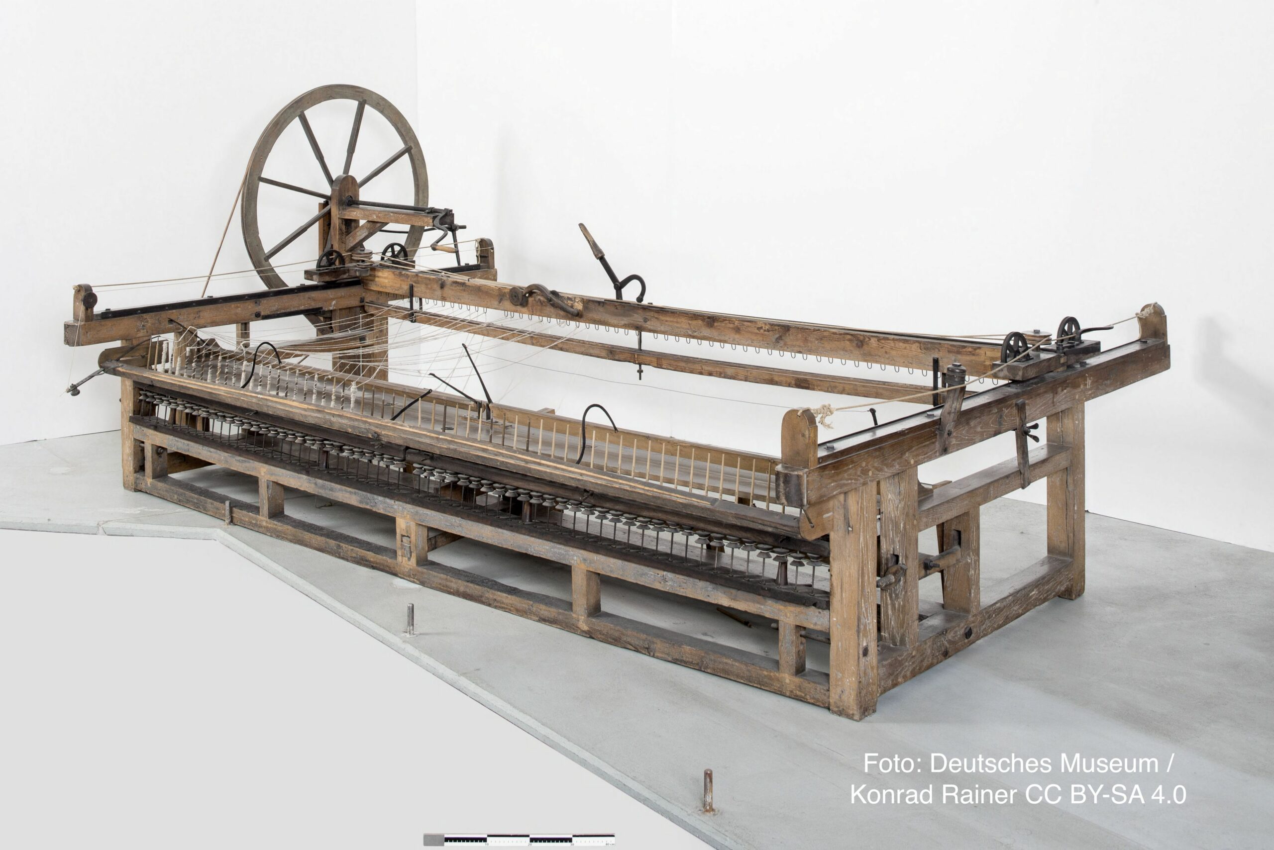 Hölzerne Spinnmaschine aus dem Jahr 1765, die vor einer weißen Wand im Museum steht